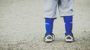 a low shot of child in sport socks and shoes on baseball field