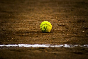 a softball on infield behind chalk baseline