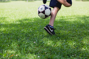 shot of feet and legs with soccer ball in grass field.